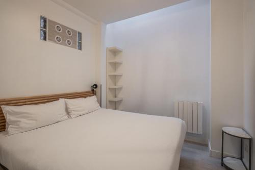 Un dormitorio con una cama blanca y un estante. en Résidence Clignancourt, en París