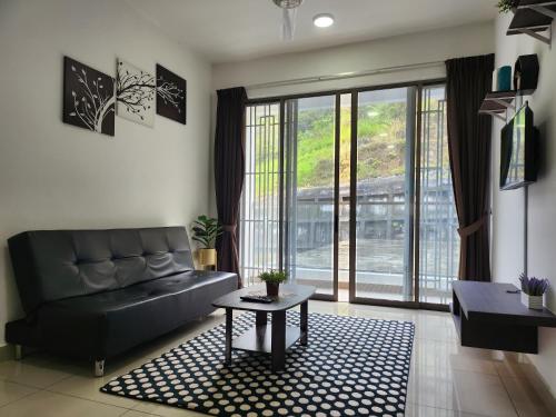 a living room with a black couch and a table at Relax Bear Homestay in Tanah Rata