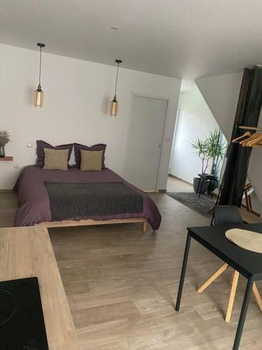 ein Schlafzimmer mit einem großen Bett und einem Tisch in der Unterkunft Studio spacieux proche gare et centre ville in Saint-Amand-les-Eaux