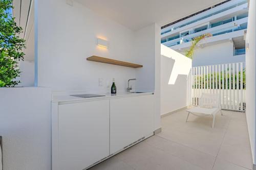 a white kitchen with a counter and a chair at Luxury triplex + pool, jacuzzi - SissiPark Azul in Acantilado de los Gigantes