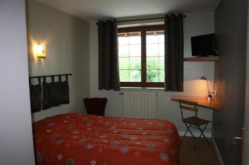 a bedroom with a bed and a desk and a window at Le Logis du Pré Braheux in Saint-Nabord