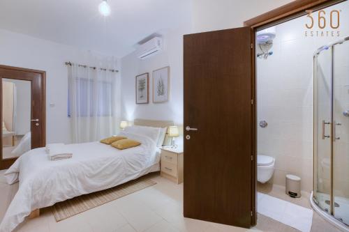 a bedroom with a bed and a bathroom with a shower at A beautiful spacious home in a picaresque location by 360 Estates in Hal Ghaxiak