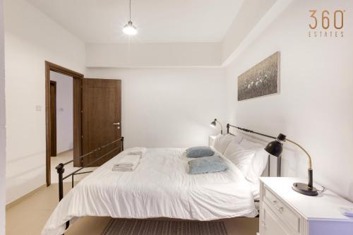 a white bedroom with a bed and a desk at A beautiful spacious home in a picaresque location by 360 Estates in Hal Ghaxiak
