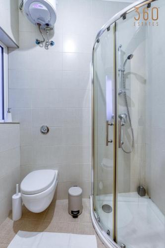 a bathroom with a toilet and a glass shower at A beautiful spacious home in a picaresque location by 360 Estates in Hal Ghaxiak