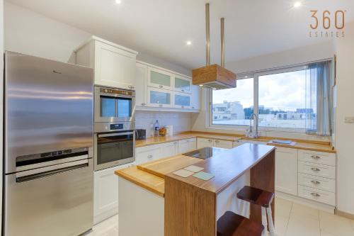 a kitchen with white cabinets and a stainless steel refrigerator at A beautiful spacious home in a picaresque location by 360 Estates in Hal Ghaxiak