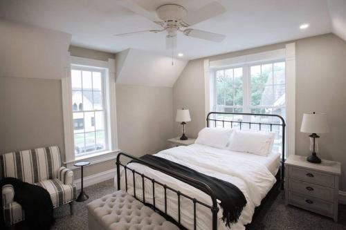 um quarto com uma cama, uma cadeira e janelas em Restored Queen Anne Cottage em Maquoketa