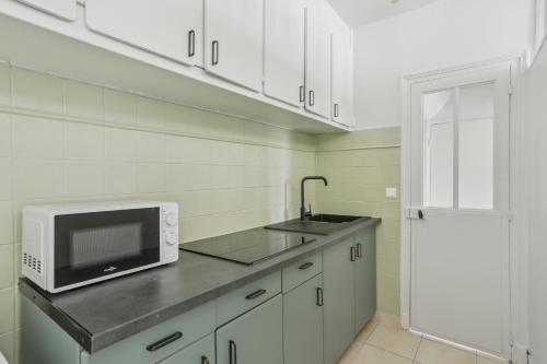 a kitchen with a microwave and a sink at Hôtel Robespierre Ex Idéal hôtel Paris - Montreuil in Montreuil