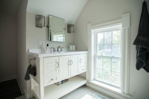 uma casa de banho branca com um lavatório e uma janela em Restored Queen Anne Cottage em Maquoketa