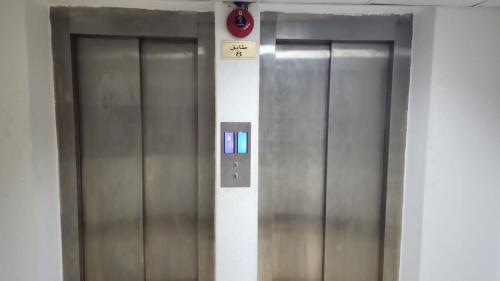 Dos ascensores metálicos con un cartel en la pared en Abu Dhabi Tourist Club-Hotel Home Stay, en Abu Dabi