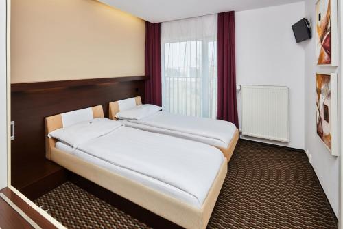2 Betten in einem kleinen Zimmer mit Fenster in der Unterkunft Hotel Rottal in Otrokovice