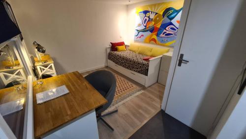 Cette petite chambre comprend une table et un canapé. dans l'établissement Le studio dans le jardin., à Rosny-sous-Bois