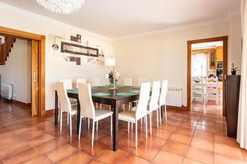 a dining room with a black table and white chairs at Can Pedra junto a Playa den Bossa in Sant Jordi