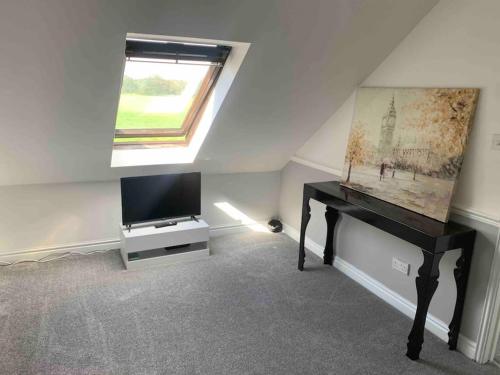 a living room with a desk and a television at Stunning remote norfolk apartment in Mileham