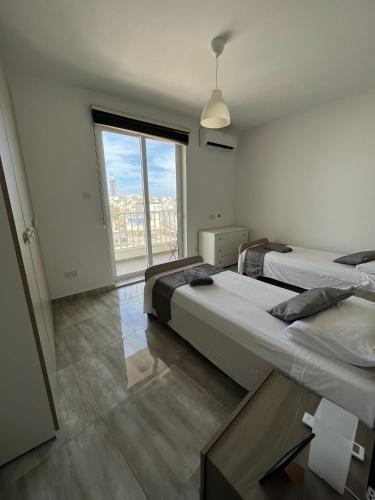 F9-3 Room 2 single beds with shared bathroom in shared Flat في مسيدا: سريرين في غرفة مع نافذة كبيرة