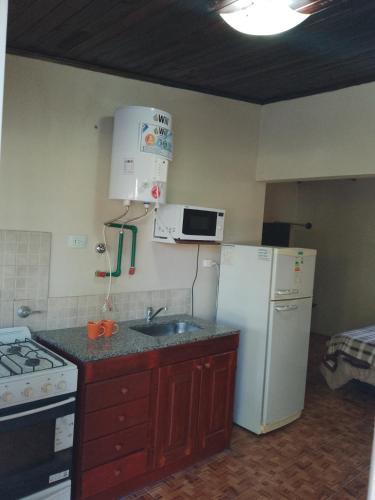 a kitchen with a white refrigerator and a sink at Cabañas Eluney in Villa Parque Siquiman