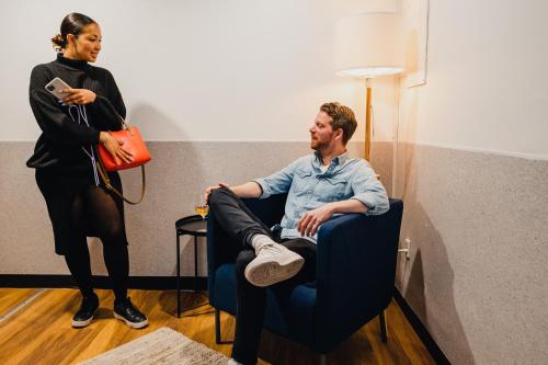 a woman standing next to a man sitting in a chair at Capsule Hotel Nyhavn63 in Copenhagen