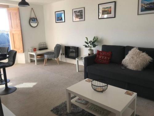 a living room with a black couch and a table at Caldey View in Tenby