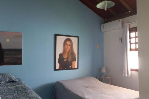 a blue bedroom with a picture of a woman on the wall at Casa de praia por temporada. in Camacari