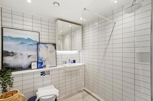 a white tiled bathroom with a sink and a mirror at 1 Bed Executive Apartment near Kings Cross & Camden FREE WIFI by City Stay Aparts London in London