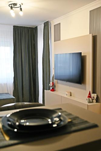 a room with a television and a table with a plate at Hedonist Centar 7 Luxury Apartments in Doboj