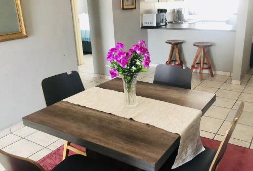 a vase of purple flowers sitting on a wooden table at @Menlyn Place, Menlyn Maine, Pretoria - Accommodation in Pretoria