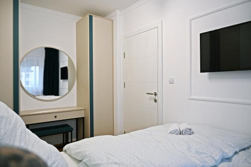 a bedroom with a bed and a mirror and a television at Hedonist Centar 7 Luxury Apartments in Doboj