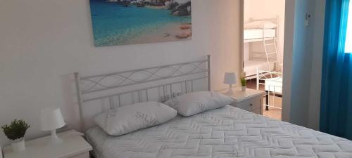 un letto bianco con due cuscini in una camera da letto di Villa Rifla Attico a Lizzano