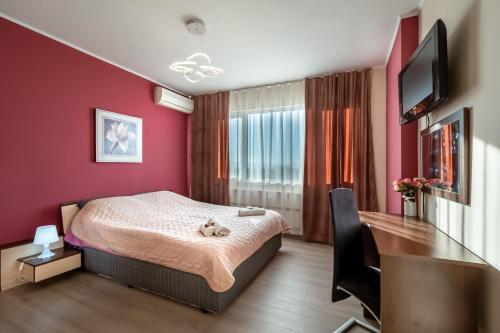 um quarto com uma cama, uma secretária e uma televisão em Apartments Rosina em Plovdiv