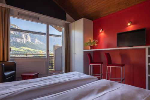 una camera da letto con pareti rosse, un letto e una finestra di Hotel des Alpes a Flims