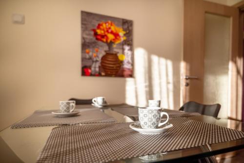 a table with two coffee cups and a vase at Apartments Rosina in Plovdiv