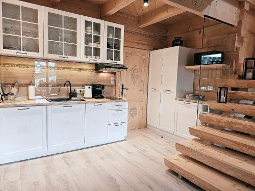 una cucina con armadietti bianchi e pareti in legno di Domek Góralski Niedźwiedzia Gawra & Sauna Zone by RentiloPL a Poronin