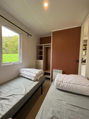 two beds in a room with a window at Lodge Camping De la vallée in Durbuy