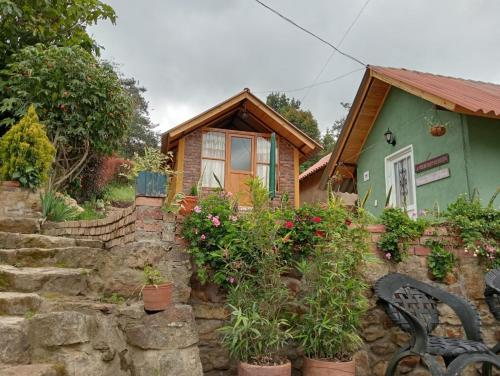 una pequeña casa con una pared de piedra y un banco en Hospedaje - Cabañas villa rosita, en Monguí
