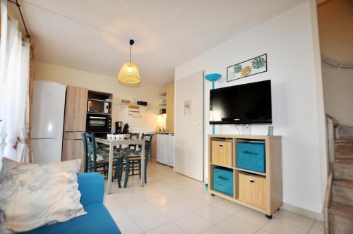 un salon avec un canapé bleu et une cuisine dans l'établissement Marina, île des pécheurs - Accès Piscine et Spa, au Barcarès