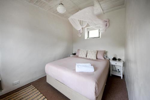 1 dormitorio con cama blanca y ventana en Devlin's Cottage en Cape Bridgewater