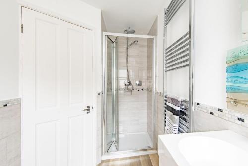 baño blanco con ducha y puerta de cristal en Samphire Cottage by Bloom Stays en Broadstairs