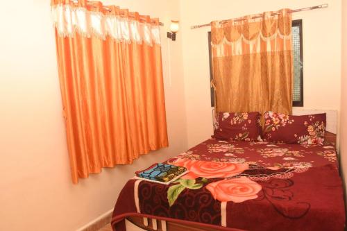 een slaapkamer met een bed met oranje gordijnen bij Bluestar cottage in Matheran