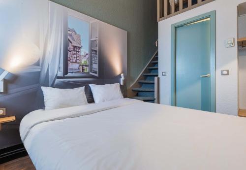 a bedroom with a white bed and a staircase at B&B HOTEL STRASBOURG Nord Industrie in Vendenheim