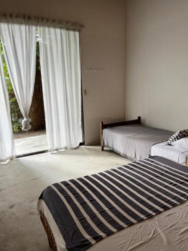 a bedroom with two beds and a large window at Pachamama Tropical Garden Lodge in Carmen