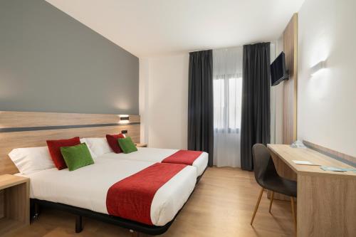 アーロにあるHotel Alda Malvasíaの赤と緑の枕が付いたベッドが備わるホテルルームです。