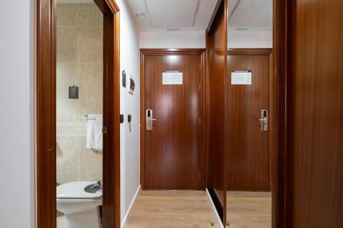 a bathroom with wooden doors and a toilet and a sink at Hotel Alda Malvasía in Haro