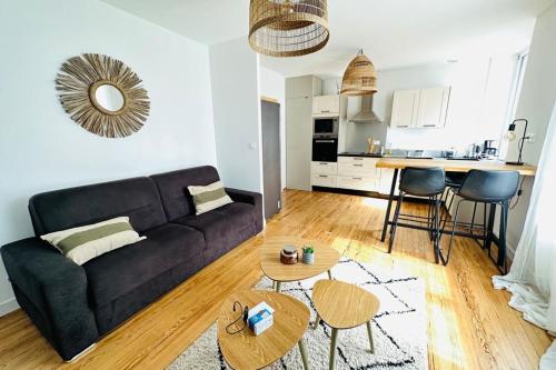een woonkamer met een zwarte bank en een keuken bij Appartement cosy - centre-ville in Lorient