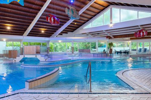 a large pool with blue water in a building at Summio Parc Heihaas in Putten