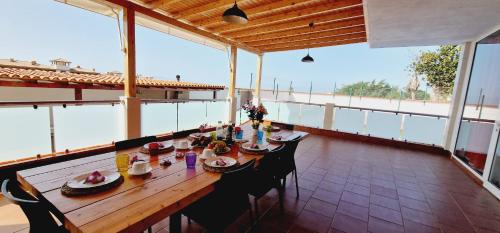 una larga mesa de madera con sillas en el balcón en Bright 4 bedroom Villa, Pool and Tennis court, en Playa Paraiso