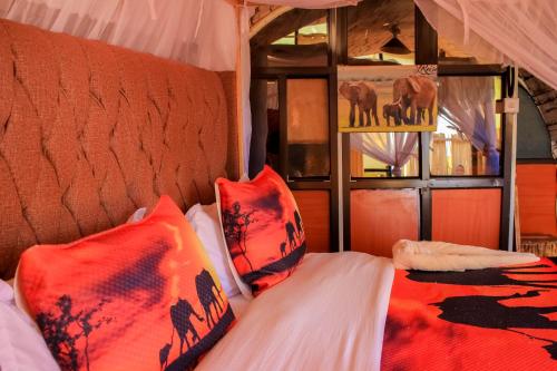 a bedroom with a bed with red pillows and a window at Amanya 1-Bed Elephant Suite Tent in Amboseli