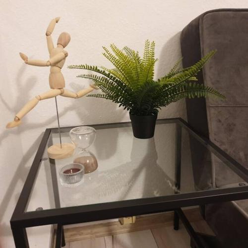 a wooden mannequin on a glass table with a plant at Schöne geräumige 3 Zimmer Wohnung in Heidelberg in Leimen