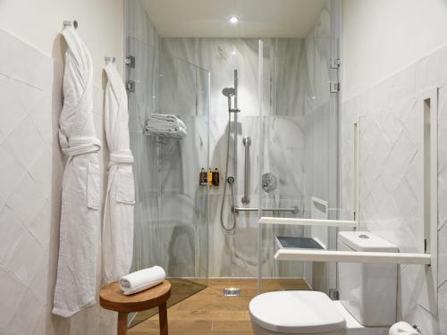 uma casa de banho branca com um chuveiro e um WC. em H10 Metropolitan 4* Sup em Barcelona