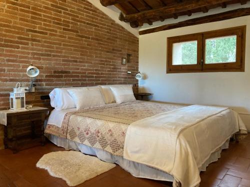 a bedroom with a bed and a brick wall at Habitación suite en Masía Can Robira in Els Hostalets