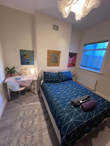 ロンドンにあるRelaxing&Cozy Roomのベッドルーム1室(青い掛け布団、テーブル付)