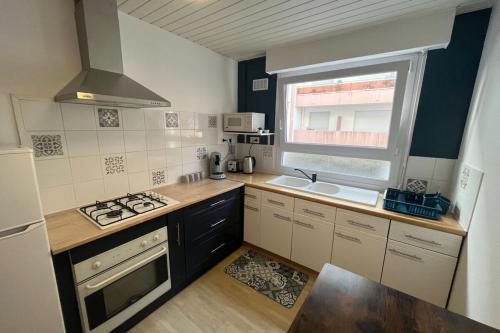 une cuisine avec un évier et une cuisinière four supérieur dans l'établissement Joli appartement proche Centre, à Lorient